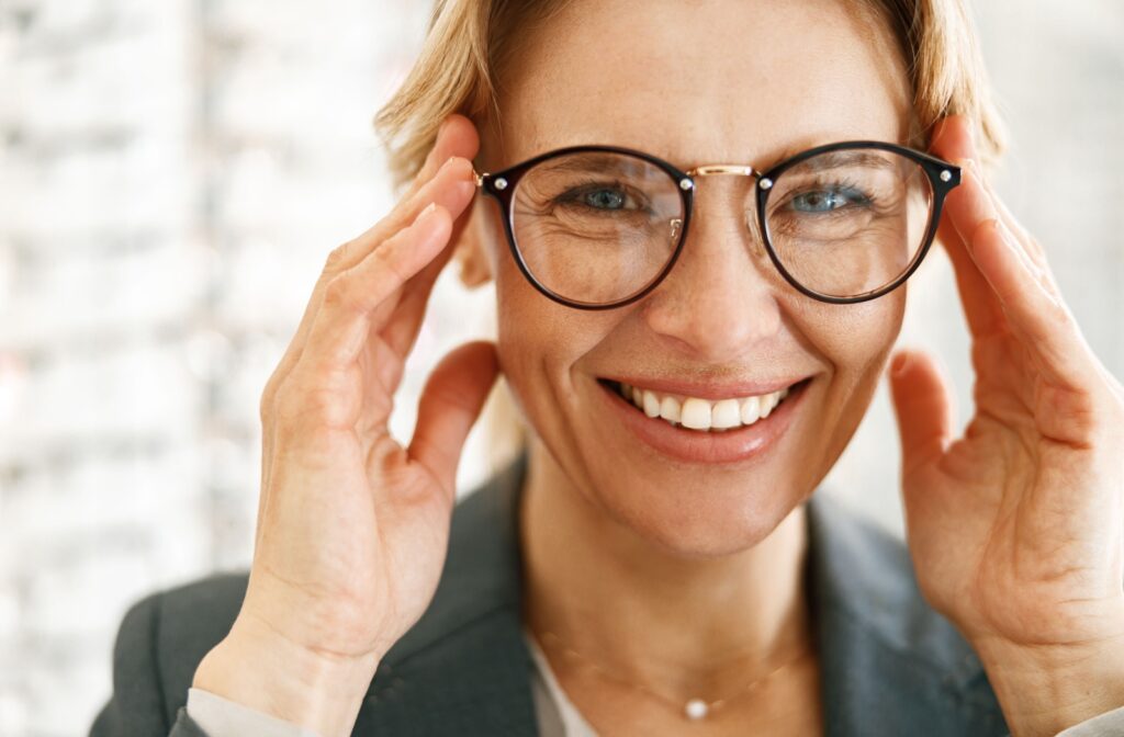 A person with a bright smile admires their new, perfectly fitting glasses.