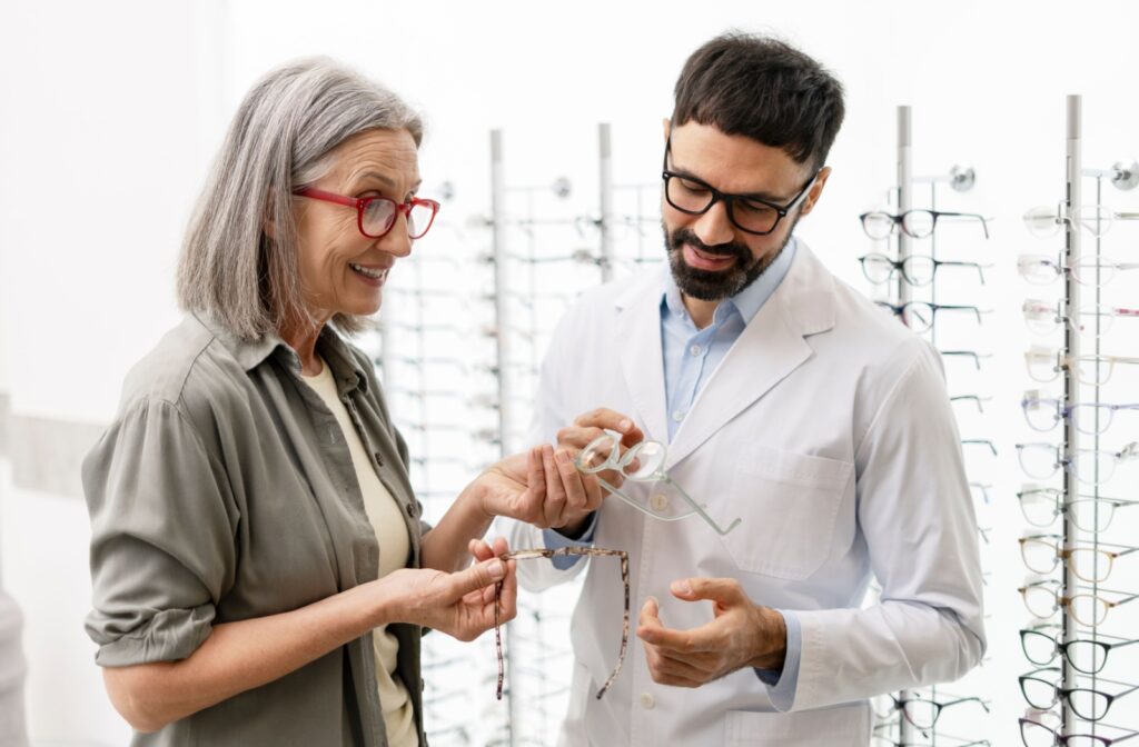 A patient wearing bold eyeglasses explores new frame options with their optometrist.