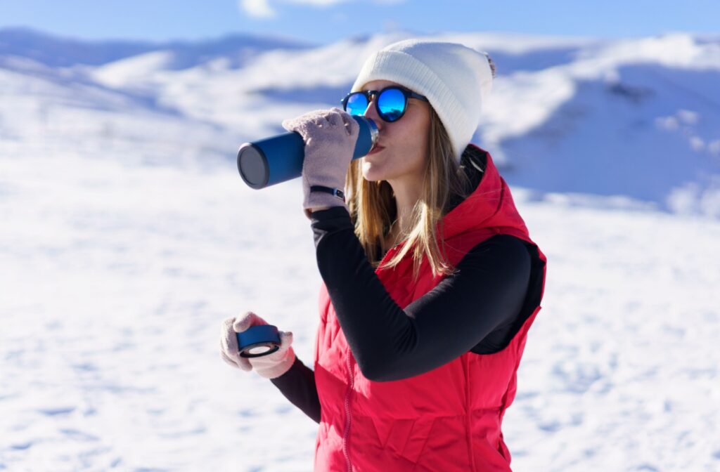 A woman wearing polarized sunglasses on a snowy mountain to reduce glare and protect her eyes.